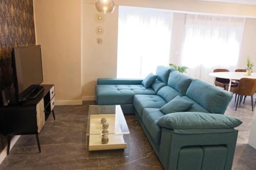 a living room with a blue couch and a table at Apartamento Suite 48- Recién reformado in Avilés