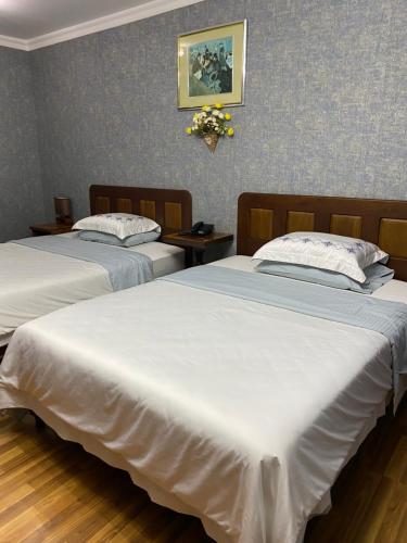 two beds in a hotel room with white sheets at Cinzano Complex in Samarkand