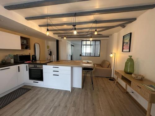 une cuisine avec des armoires blanches et une table dans une pièce dans l'établissement Appartement moderne avec jardin et parking, à Vannes