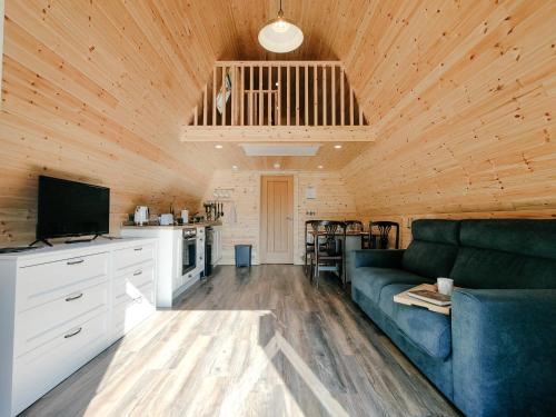 a living room with a blue couch and a kitchen at Bective Mill Glamping & Camping 