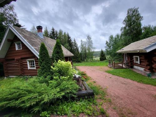 a log cabin with a dirt road next to a house at Hirsitalo ja -sauna in Nummi