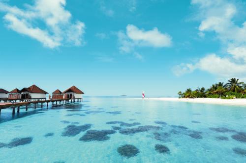 a beach with a pier and houses on the water at ROBINSON MALDIVES - Adults only in Gaafu Alifu Atoll