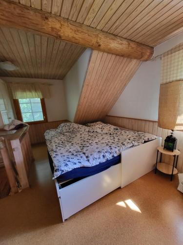 Hirsitalo ja -sauna في Nummi: سرير في غرفة ذات سقف خشبي