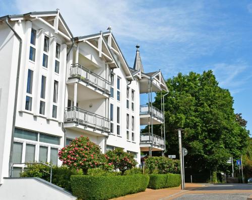 a white building with balconies on a street at Appartementhaus mit Balkon im Ostseebad Göhren HM-10-18 in Göhren