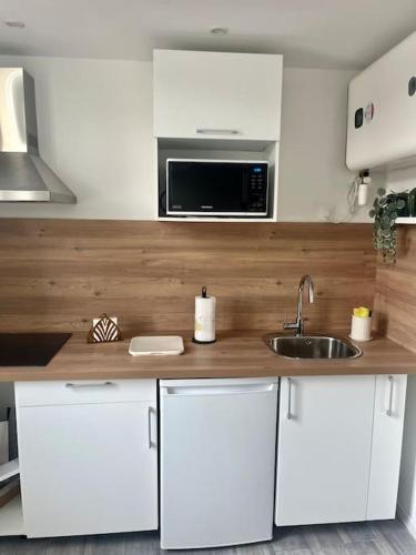 une cuisine avec des armoires blanches, un évier et un micro-ondes dans l'établissement Studio cosy refait à neuf, à Marseille