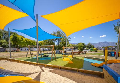 a playground with a slide and an umbrella at Omarama TOP10 Holiday Park in Omarama