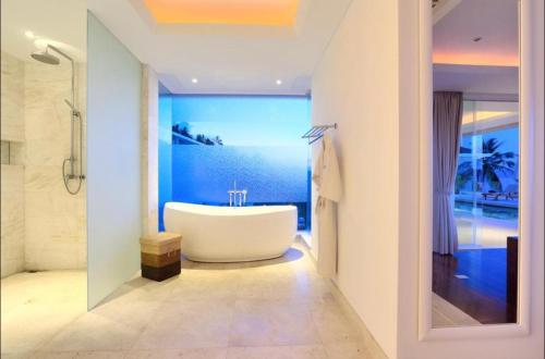 La salle de bains est pourvue d'une baignoire blanche et d'un mur bleu. dans l'établissement White Tiger Villa, à Koh Samui 