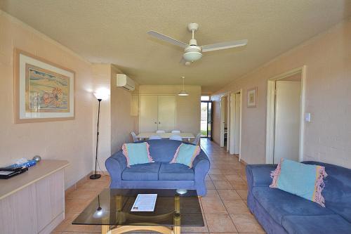 a living room with two blue couches and a table at Riverview Holiday Apartment 47 - Kalbarri, WA in Kalbarri