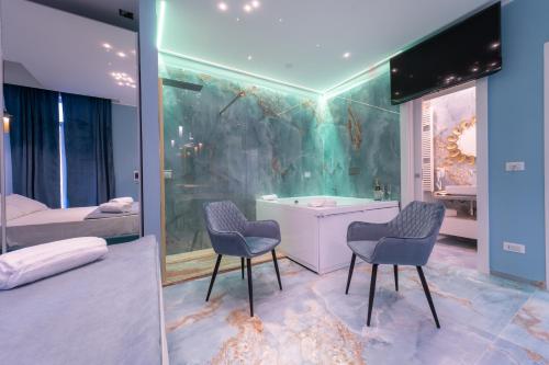 a bathroom with a tub and two chairs and a bedroom at Suite Acquamarine Dimora Stapane in Gallipoli