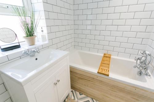 a white bathroom with a tub and a sink at Treforris in Rhosneigr