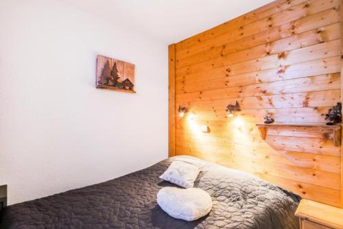 - une chambre avec un lit et un mur en bois dans l'établissement Résidence Les Sentiers du Tueda - maeva Home - 2 pièces 4 Personnes Confort MAE-9336, à Les Allues
