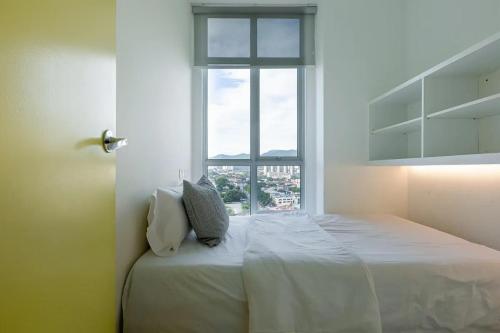 a white bedroom with a bed and a window at Straits Garden Suites Penang in Jelutong