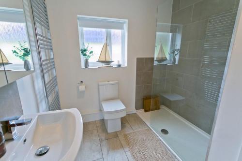 a bathroom with a toilet and a shower and a sink at Ty Glan Y Mor in Aberffraw