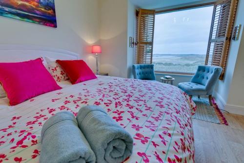 a bedroom with a large bed with pink and red pillows at Seaforth in Rhosneigr