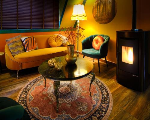 a living room with a couch and a table and a fireplace at Boshuisje Pinus Sonnevijver Residences in Lanaken