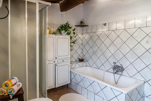 a bathroom with a tub and a white tiled wall at Querciagrossa da Dora in Roccastrada