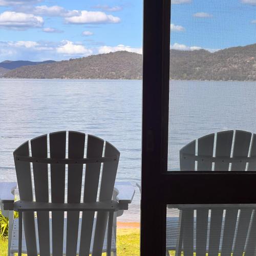 two chairs sitting in front of a view of the water at Deerubbin Boat House in Dangar Island