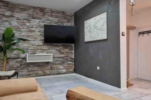 sala de estar con pared de piedra y TV de pantalla plana. en Les Suites du Palais, en Carcassonne