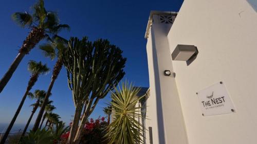 a white building with palm trees and a sign on it at The Nest Tenerife in Arona