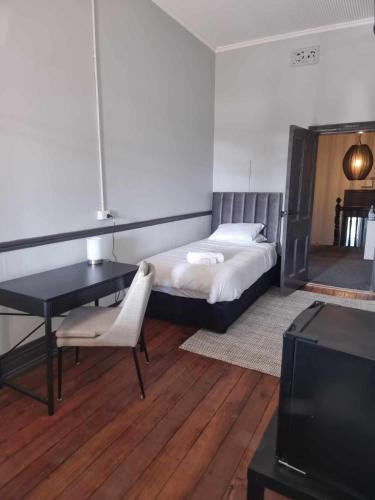 a bedroom with a bed and a desk and a tv at The Federal Hotel in Kalgoorlie