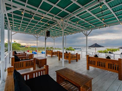 a patio with wooden benches and tables and a television at Nusa Indah Onai Hotel in Nusa Lembongan