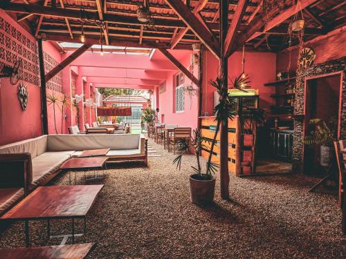 Zimmer mit rosa Wänden, Sofa und Tischen in der Unterkunft La Casa Moz in Maputo