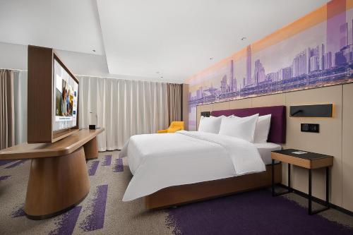 ein Hotelzimmer mit einem großen Bett und einem TV in der Unterkunft Hampton by Hilton Guangzhou Railway Station in Guangzhou