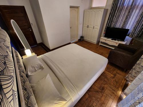 a large white bed in a room with a television at La Casa Moz in Maputo