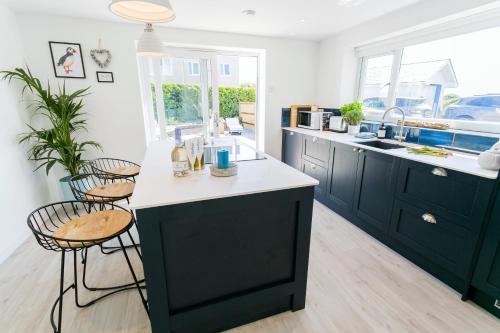 a kitchen with black cabinets and white counter tops at Y Bwthyn in Rhosneigr