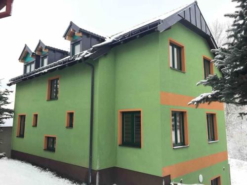 a green building with snow on the ground at Chata Mamutka-New in Loučná pod Klínovcem