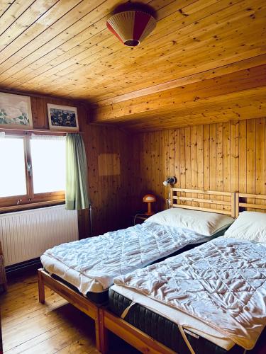 a bedroom with two beds in a wooden cabin at Chalet Waldwiese - CharmingStay in Flumserberg