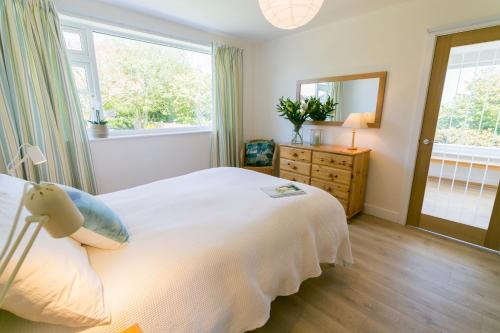 a bedroom with a white bed and a window at Ynys Las in Valley