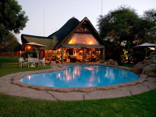 a swimming pool in front of a house at Ditholo Game Lodge Bela Bela in Bela-Bela
