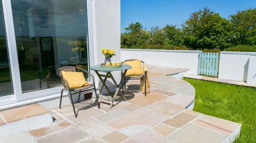 a patio with two chairs and a table with flowers at Ynys Las in Valley