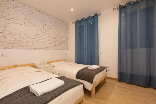 2 camas en una habitación con cortinas azules en Gothic - Ramblas Apartments, en Barcelona