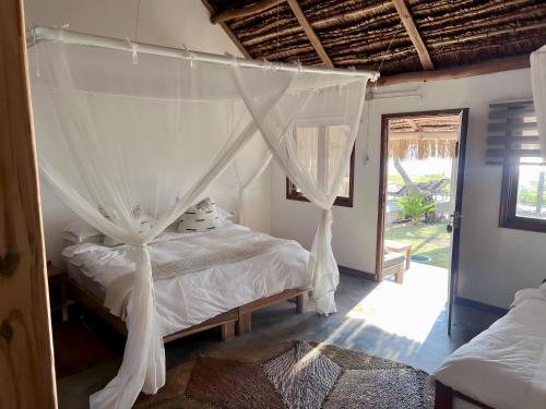 a bedroom with a bed with a mosquito net at Blu at tofo in Praia do Tofo