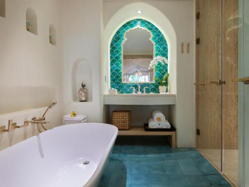 een badkamer met een bad en een spiegel bij Bali Mandira Beach Resort & Spa in Legian