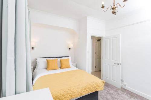 een witte slaapkamer met een bed met gele kussens bij 20 Montpellier Flat 2 in Cheltenham