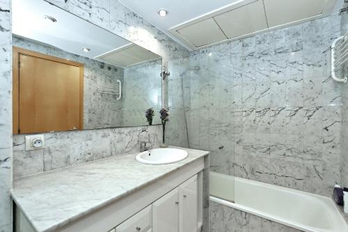 uma casa de banho com um lavatório, uma banheira e um espelho. em Apartament Sant Feliu em Girona