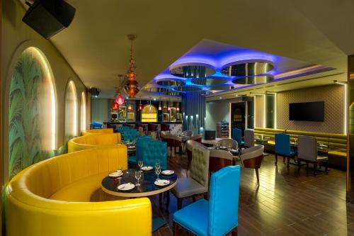 a restaurant with yellow and blue chairs and tables at Cygnett Inn Imperial Tezpur in Tezpur