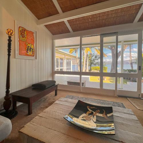 a living room with a bench and a large window at Deerubbin Boat House in Dangar Island