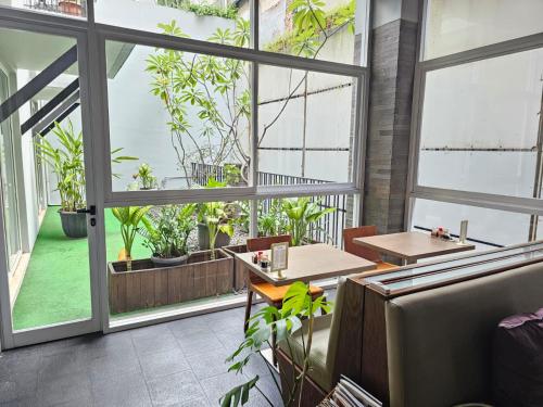 un restaurante con grandes ventanas, mesas y plantas en Via Renata Panglima Polim en Yakarta