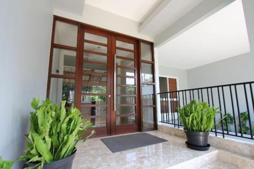 a balcony with a wooden door and two potted plants at Via Renata Panglima Polim in Jakarta