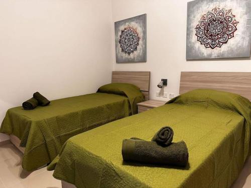 Habitación con 2 camas con sábanas verdes en Cozy, Spacious 3 Bedroom Maisonette, 6 to 9 ppl, 1 min walk from Seafront en Marsaxlokk
