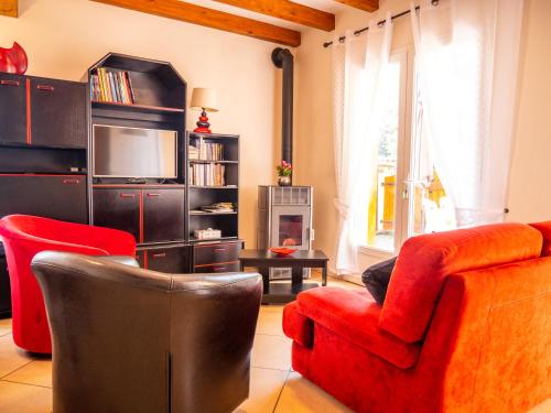 a living room with a red couch and a television at Maison de vacances in Bompas
