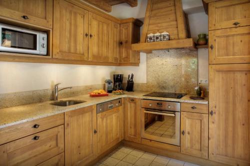uma cozinha com armários de madeira e um lavatório em Chalet Hollygotty - OVO Network em La Clusaz