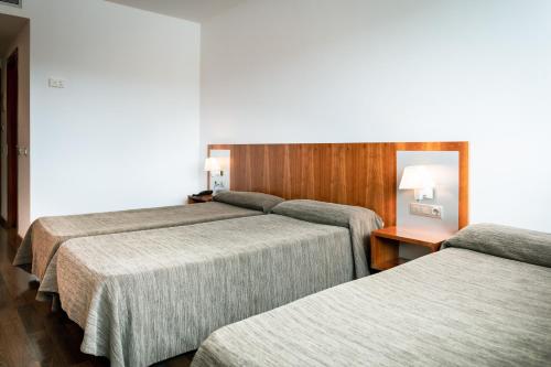 a hotel room with three beds and a table at AS Porta de Barcelona in Castellbisbal