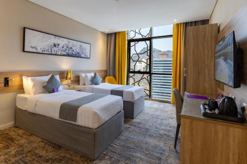 a hotel room with two beds and a large window at Anan Hotel By Snood in Makkah