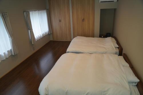 two beds in a small room with wooden floors at LOOP-shiso in Shiso