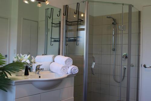 a bathroom with a sink and a shower with towels at McLaren Lake View in Tauranga